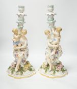 A pair of German floral encrusted porcelain candlesticks of a mother and child group, 38cm high