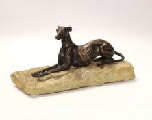 A bronze model of a recumbent greyhound on a rough-hewn limestone base, 27cm long