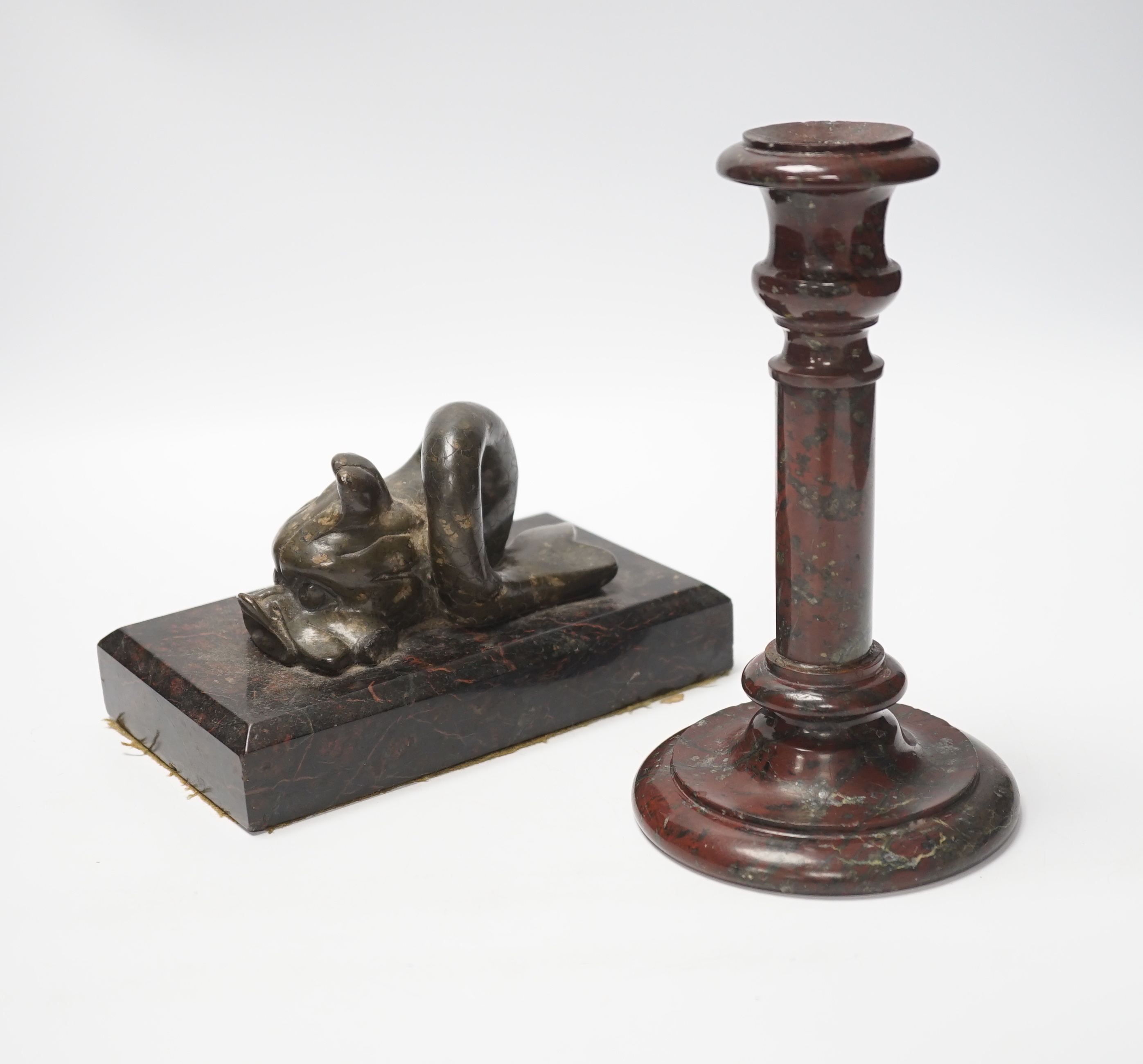 A 19th century serpentine candlestick and a carved dolphin paperweight, tallest 20cm high