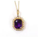 An Edwardian 15ct, amethyst and seed pearl cluster set pendant, overall 33mm, on a 9ct chain,