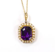 An Edwardian 15ct, amethyst and seed pearl cluster set pendant, overall 33mm, on a 9ct chain,