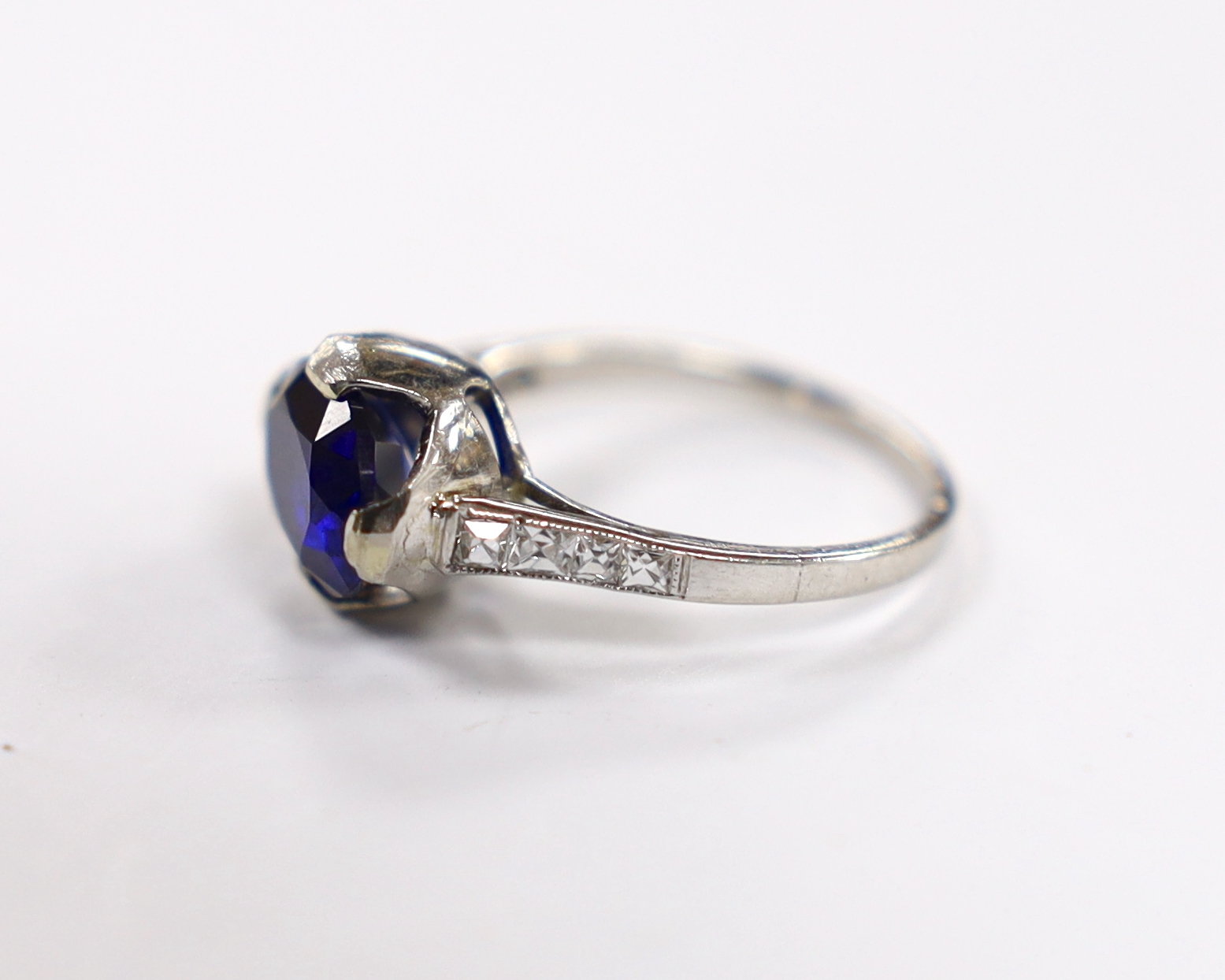 A plat. and iridium, single stone oval cut synthetic sapphire set ring, with graduated diamond - Image 2 of 3