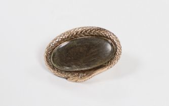 A Victorian yellow metal mounted oval mourning brooch, with plaited hair beneath a glazed panel