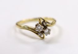 A yellow metal and graduated four stone diamond set crossover ring, size R, gross weight 3.4 grams.
