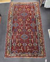 A Caucasian burgundy ground rug, 220 x 128cm