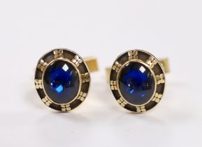 A pair of yellow metal and blue cabochon paste set cufflinks, the backs inscribed 'Jostens 10k', the
