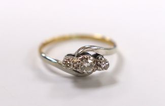 A yellow metal and three stone diamond set crossover ring, size H/I, gross weight 2 grams.