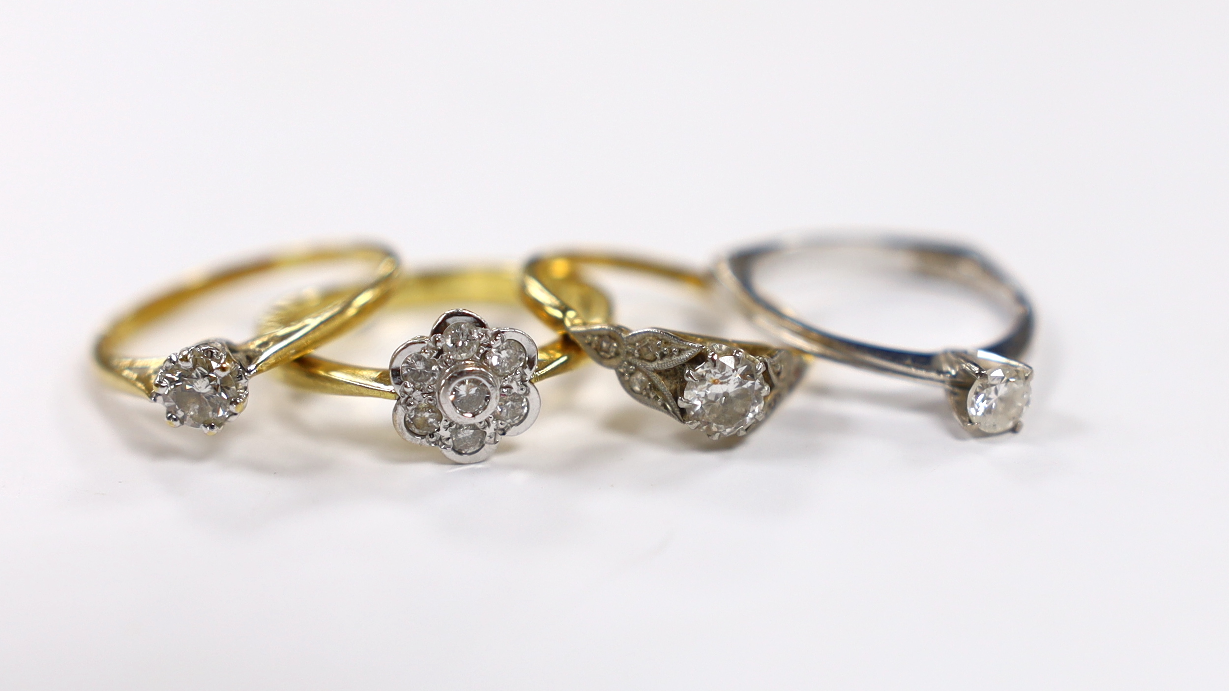 Three assorted 18ct and solitaire diamond rings and an 18ct gold and diamond set flower head ring,