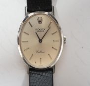 A lady's modern 18k Rolex Cellini manual wind oval wrist watch, with baton numerals, on a leather