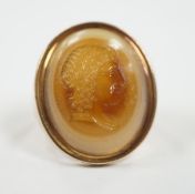 An early 20th century yellow metal and banded agate intaglio ring, carved with the head of a