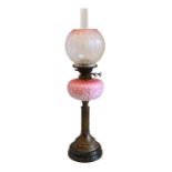 A late Victorian brass and black ceramic oil lamp with opaque moulded pink glass reservoir, Best