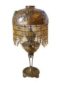 An early 20th century cast bronze and brass oil lamp with coloured glass gem inset domed and