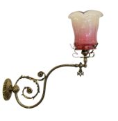 A late Victorian cast brass gasolier wall light, now converted to electricity, with a cranberry