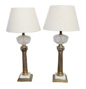 A pair of brass and white marble table lamps modelled as oil lamps with glass reservoirs, fitted