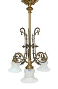 An early 20th century French brass light fitting with foliate scroll design and three opaque