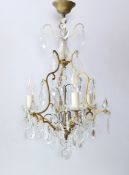 A French gold painted wrought iron and glass chandelier hung with cut and facetted glass drops,