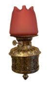 An Edwardian lacquered brass wall mounted oil lamp, with Duplex mechanism and frosted cranberry