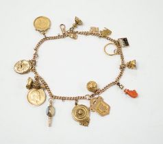 A 9ct gold curblink chain hung with fifteen assorted charms including a 1906 sovereign and an 1865