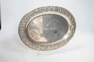 A Thai white metal oval salver, the border decorated with flowers, birds and squirrels, stamped