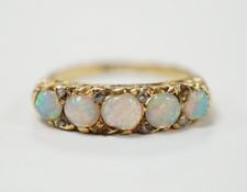 A late Victorian yellow metal and white opal five stone ring with diamond chip set spacers, size M