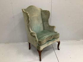 An 18th century upholstered wing armchair on carved walnut cabriole legs, width 80cm, depth 70cm,