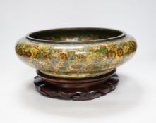A Chinese circular cloisonné enamel bowl decorated with multi-coloured flowerheads on wooden
