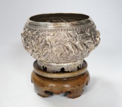 An Indian circular white metal bowl, decorated with a continuous band of figures in a landscape,