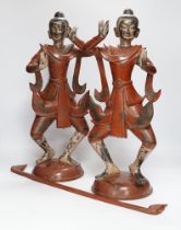 A pair of Thai red ochre painted bronze figures of traditional dancers with decorative rod on