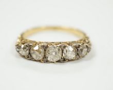 An early 20th century yellow metal and graduated five stone diamond set half hoop ring, with diamond
