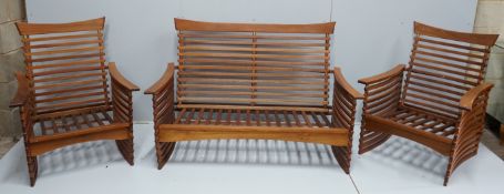 In the manner of Finn Juhl, a Danish brass mounted teak three piece lounge suite of slatted form,