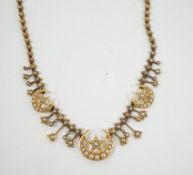 An Edwardian yellow metal and seed pearl set drop necklace, with star and crescent motifs, lacking