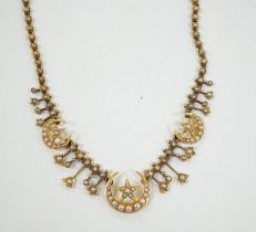 An Edwardian yellow metal and seed pearl set drop necklace, with star and crescent motifs, lacking