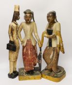 A pair of Indonesian painted carvings, two females and another, largest 44cm high