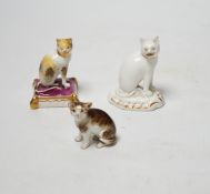 Two Rockingham porcelain models of seated cats, c.1830, the cat seated on a maroon cushion with