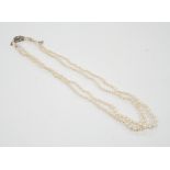 A 1940's double strand graduated cultured pearl necklace, with diamond set white metal clasp, 46cm.