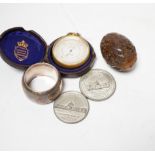 A Lennie brass pocket barometer, a carved coquilla nut, a silver plated napkin ring and two