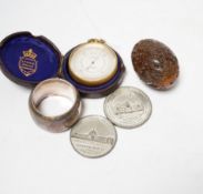 A Lennie brass pocket barometer, a carved coquilla nut, a silver plated napkin ring and two