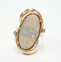 A yellow metal and oval cut black opal set dress ring, with two stone diamond chip set border,