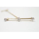 A yellow metal and three stone diamond set bar brooch, 37mm, with safety chain, gross weight 3