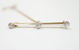 A yellow metal and three stone diamond set bar brooch, 37mm, with safety chain, gross weight 3