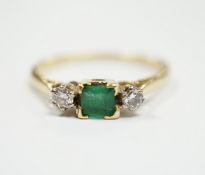 An 18ct and plat, single stone emerald and two stone diamond set ring, size Q/R, gross weight 2.6