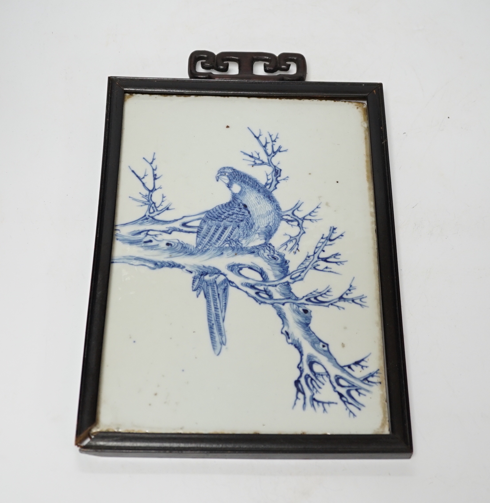 A late 19th century Chinese blue and white plaque of a bird, ebonised frame, 19cm wide x 30cm high