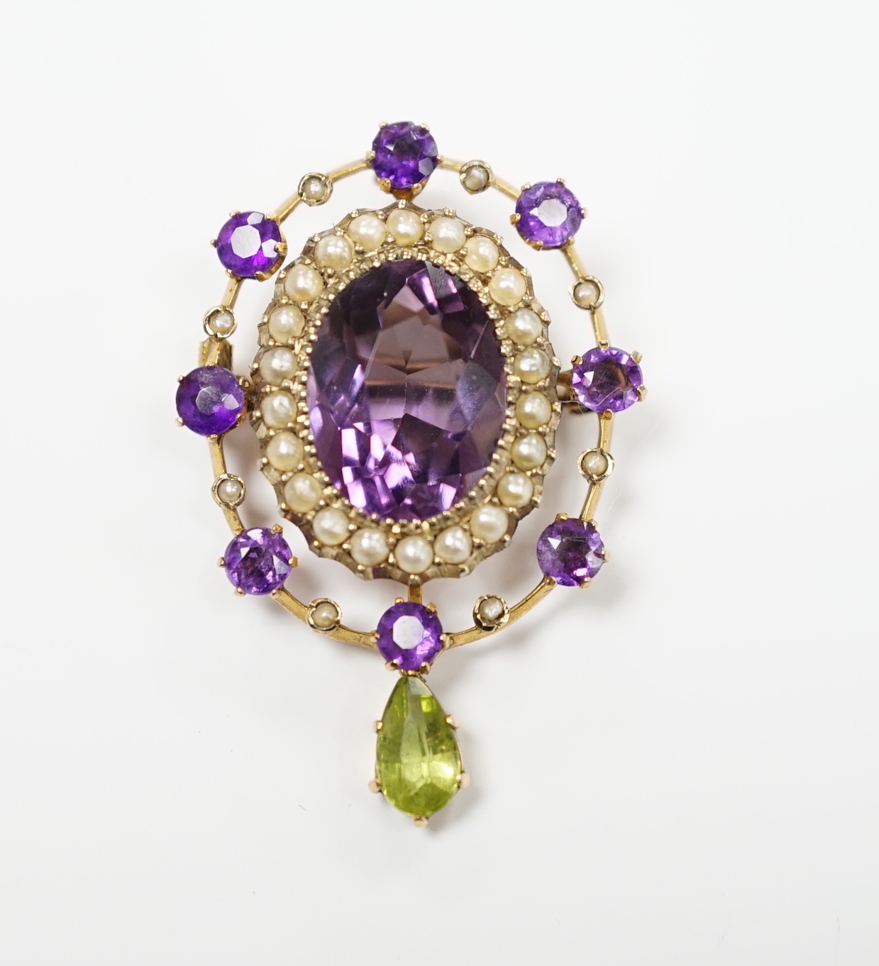 An early 20th century yellow metal, amethyst, peridot and seed pearl cluster set drop pendant