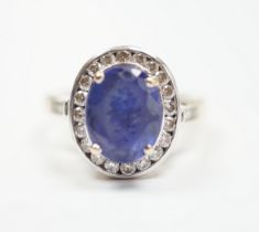 A modern 750 and oval cut single stone tanzanite(worn) set dress ring, with diamond set border and