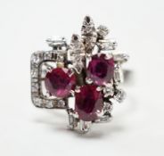 A recent 18k white metal, ruby and diamond cluster set modernist dress ring, size N/O, gross