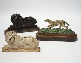 Two cast iron lion door stops and a painted dog door stop, 21cm wide