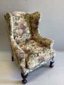 An early 20th century upholstered wing armchair on claw and ball feet, width 80cm, depth 76cm,