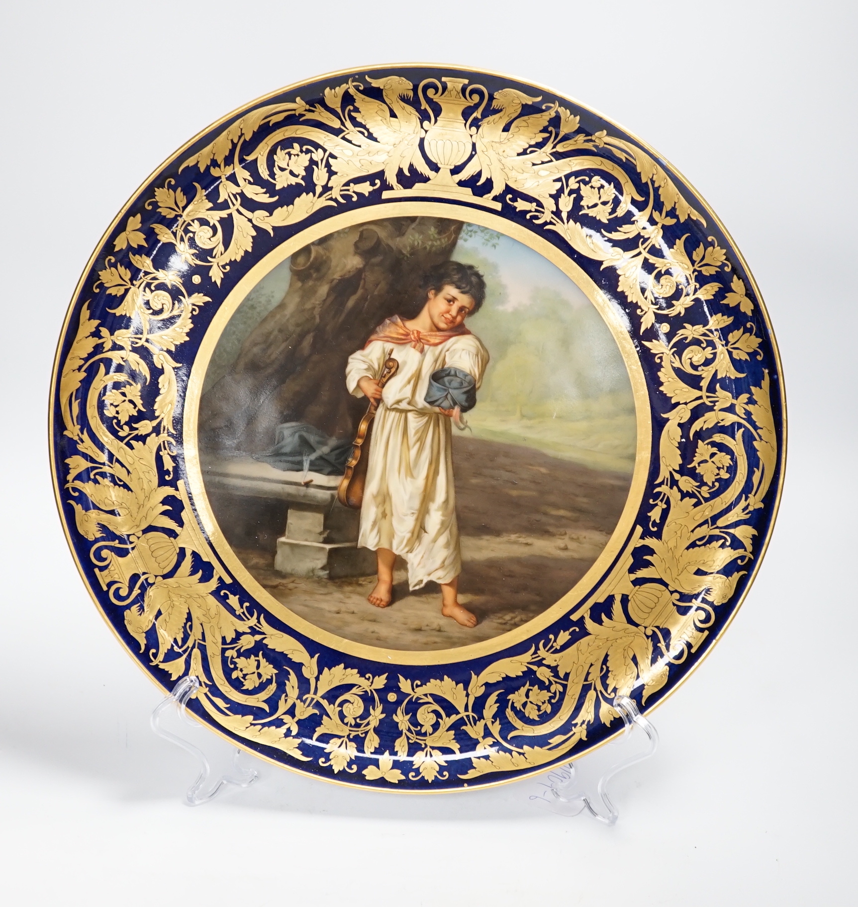 A Vienna style blue porcelain plate hand painted with a young child in a landscape, 36cm diameter