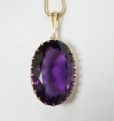 A yellow metal mounted single stone oval cut amethyst set pendant, 35mm, on a yellow metal chain,