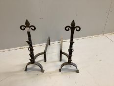 A pair of tall wrought metal fleur de lys fire dogs, height 67cm